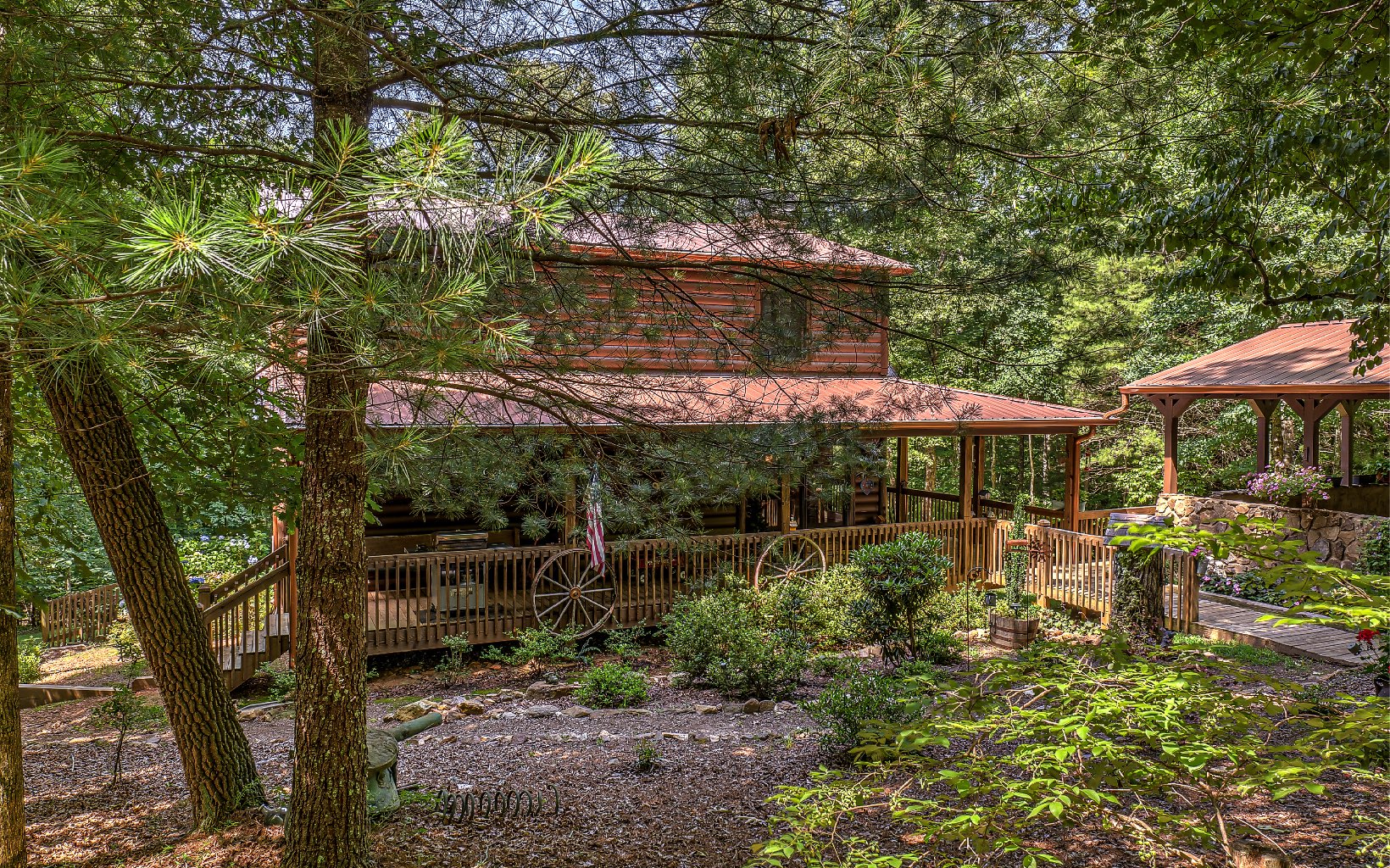 This private estate on over 5 acres features a custom built cabin, a guest cabin, large workshop & more. If you are looking for a gorgeous setting & privacy, this is it. Just driving up the driveway feels like you’re in a park, with the cabin's gardens, porch that wraps around 3 sides, new metal roof, extended porches, an oversized carport w/ stone features, & walking trails. Inside is an open living area w/ a vaulted ceiling, tall masonry fireplace, Windsor windows, kitchen w/ bar & log features, 2 bedrooms, a loft library/office, wood beam ceilings, large bathrooms with custom vanities, tile shower, double vanity, walk in closet, and more. The basement is unfinished but has a bathroom and is ready for an additional bedroom and game/family room. This cabin is very well maintained, whole house generator, 3 septic systems, fiber internet, new hvac, and seasonal mountain view. This property is 4 miles from Springer Mountain and located in between Ellijay and Blue Ridge.
