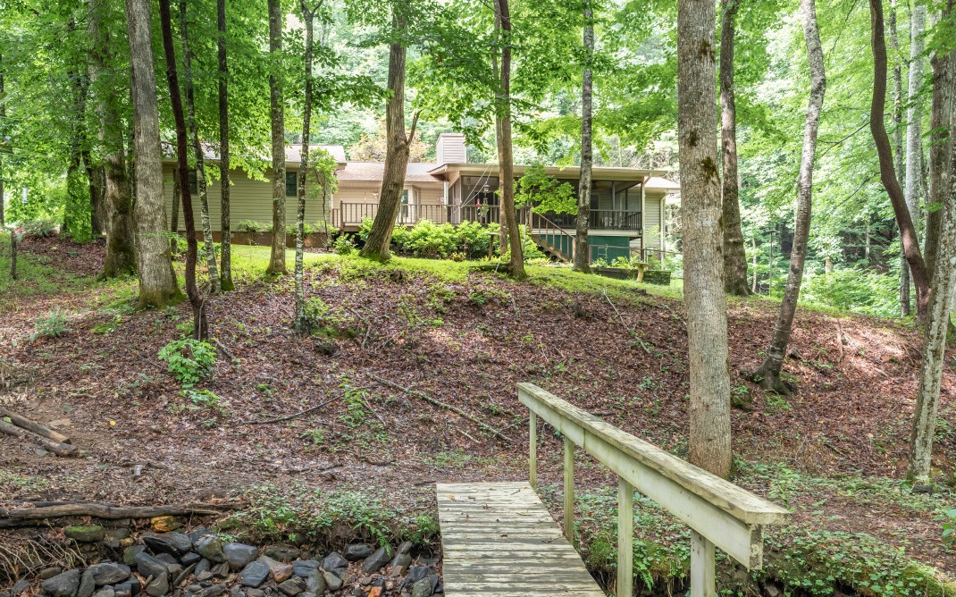Nestled among the trees of a wooded lot complete with sounds & views of a nearby flowing creek and pond is this vinyl-sided ranch home in The Ridges community. Find respite on the screened-in porch, uncovered deck, or in the yard, tending to one of the many flower beds. Come inside to an expansive living room w/ a gas log fireplace with rock wall, built-ins, bay window overlooking the deck, barn door, & dining area which flows into the oversized kitchen. The latter of which features granite countertops, custom cabinetry, & gas cooktop. Owner’s suite on the main level w/ full bath and door to screened deck. 2 additional BRs including another suite with walk-in closet, dbl sinks, jacuzzi tub, and separate shower. Terrace level laundry hookup, bonus room and storage space. Attached 2-car garage PLUS separate 2-car garage w/ storage area. You’ll find plenty of space to spread out & relax!