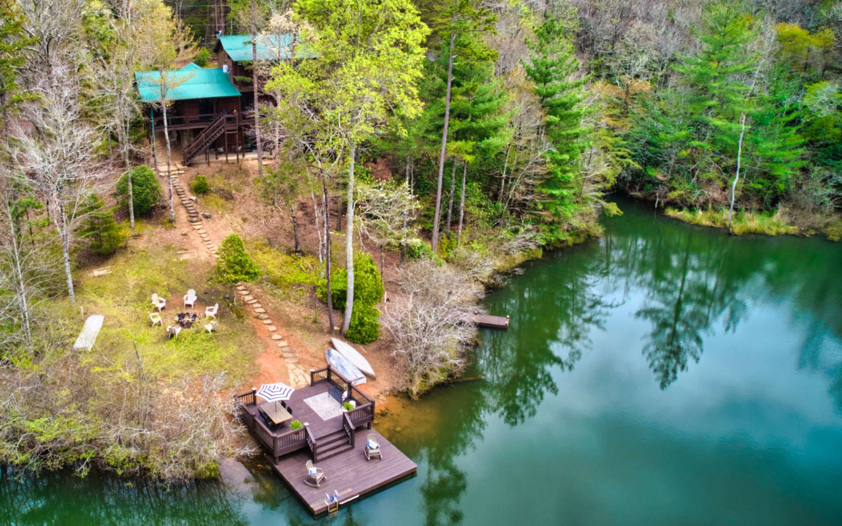 Back on the market at no fault of the sellers. Your own personal LAKEFRONT PARADISE awaits you in the N Ga Mountains! This cabin sits on a 4 AC lake minutes away from DT Blue Ridge and has absolutely everything you’re looking for! A large two level dock, separate fishing dock,3 levels of outdoor living space, more than 1,000sq ft of freshly stained wrap around porches, a wet bar, hot tub, even an outdoor shower. The cabin is being sold turn key, fully furnished and sleeps 8 comfortably. This beauty has a Gross Rental Booking history of over $80k, just in its first year. Spectacular three-level home has a huge living room with a floor-to-ceiling stone fireplace, separate dining area, amazing stairway w/custom-made mountain laurel balusters, a stone archway entry to the kitchen, stainless steel appliances, granite countertops, farmhouse kitchen sink, and wide plank pine wood floors. Master bedroom has a fireplace, sitting area, private balcony, and walk-in closet. 2 more roomy bedrooms in the finished walkout basement along w/ fireplace, media/family room, and game table area. Be ready to spend lots of time on the two lake docks. Go canoeing, paddleboarding, swimming, and fishing! Roast marshmallows at the firepit or just relax and take in the spectacular sunset views. Terrific rental history and still on a very active rental program! Start making a return on your investment today!