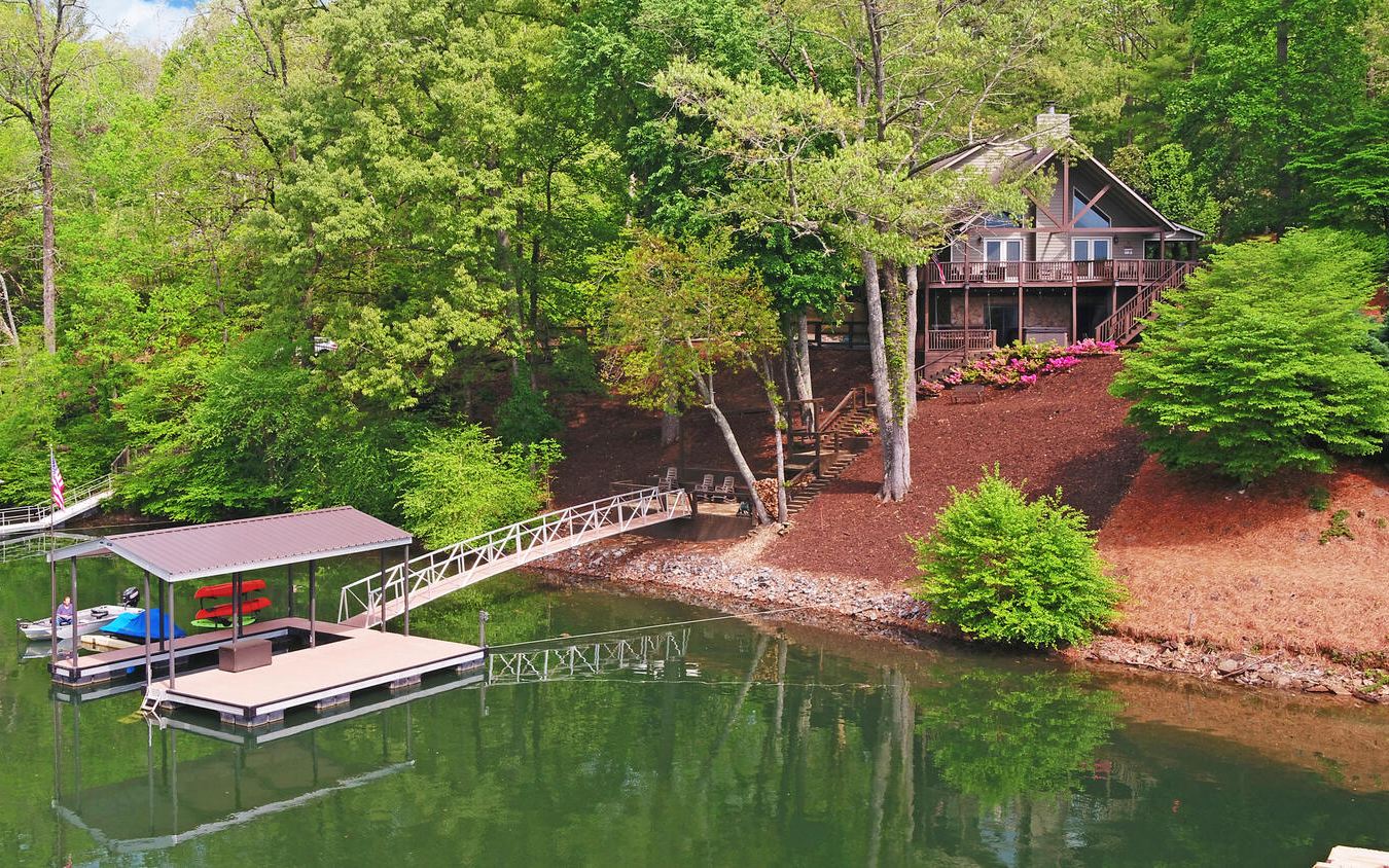**Beautiful, completely furnished lakefront home in Premier Lakefront community of Stonecrest on Lake Chatuge. Unique 4BR/4BA home has wonderful lake & mountain views, a light & airy feel, wood floors, fireplace, open kitchen, granite counters in kitchen & baths, wrap-around porch, hot tub & lakefront landing with firepit.**Soaring ceilings and lots of glass to take advantage of the wonderful view.**130' of shoreline with large single-slip covered dock with large swim deck.**Extra-large 24’x36’ garage across the road for storage or would make a great workshop.**Property lies on both sides of the road.**Many upgrades. Move-in ready.**Septic is approved for two bedrooms.**Currently a VRBO rental property with very good rental history.**Seller states average VRBO income is $9,000/month!**