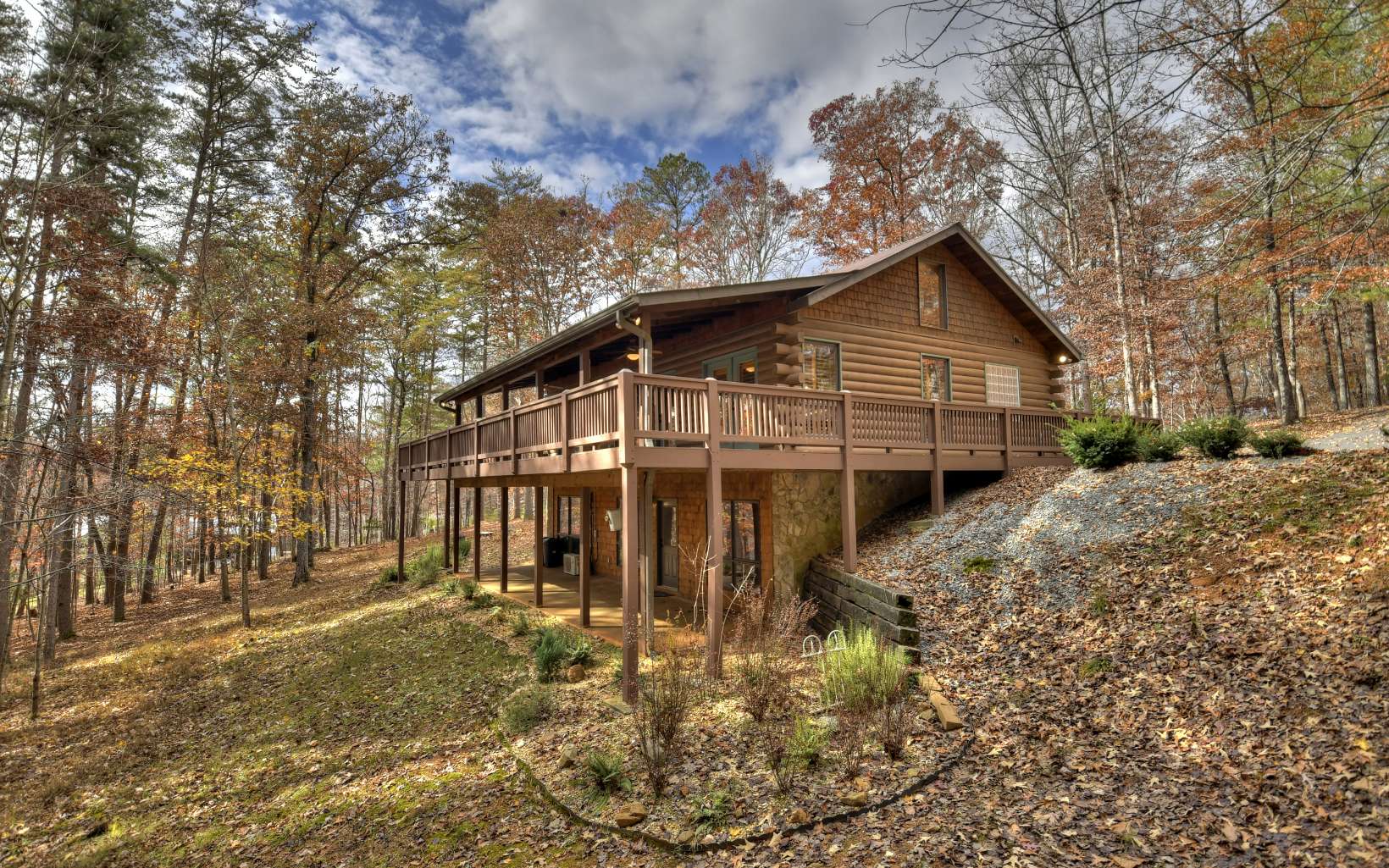 Tucked away in the beautiful Riverwalk on the Toccoa, this 3BR/3BA true log home is the answer to your mountain living dreams. Once behind the gates of Riverwalk, you'll continue the all paved drive to this hidden gem. You'll notice an asphalt circle drive, wrap around porch, porte-cochere, metal roof, and wooded back yard for privacy and low maintenance upon arrival. Once moving inside you'll soak in the warm and inviting feel with two suites on the main floor (complete with access to the back deck), along with the large wood burning stone fp & spacious kitchen, living room & dining area. This open concept living is highlights the plentiful light, custom cabinetry and other beautiful features you'll enjoy. On the terrace level, you will find the 3rd BR & BA, family/game room & large covered concrete patio. Other highlights include amazing community area with river access, boat ramp, tiki bar/kitchen, large pavilion that boasts a stunning rock fireplace, hiking trails along the rushing waters of the Toccoa & more. With no short term rentals allowed, you will enjoy your full time retreat or own mountain escape with additional privacy and security!