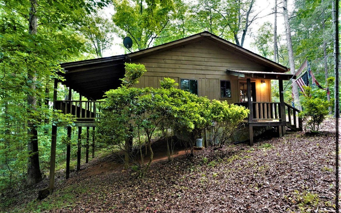 Just 15 minutes from Carter's Lake and down the street from the Coosawattee and Cartecay River! This cabin has privacy and seclusion in the mountains with no HOA, no restrictions, a private, level yard that it sits way back from the road, and no neighbors in sight! Wooded lot with little to no landscaping or maintenance, original hardwood floors, walls, and exposed beam ceiling with skylights, vaulted ceilings, a large covered back deck, stacked stone fireplace with woodburning stove insert, remote controlled lighting and ceiling fans, glass sliding doors with access to back deck from bedroom and living room, office with picture windows all around at desk level, real wood doors, cabinets, and closets (all gloss stained) no painting ever, no one knocking at the door. Large corner 1.24 acre lot that sits way offset from the corner and way back from the road. The cabin is the perfect size for those looking to heat and cool less area, less home maintenance, easy to get around and clean, yet still plenty of space to organize things, and has many special touches. This is not just a simple looking old cabin, come check it out to see that it has a lot of character. The cabin would be particularly good for someone needing an easier life with less utility costs, and less rules. The cabin has been well maintained by the owner, and is move in ready. All appliances and stacked washer and dryer stay! It is so rare to find privacy and seclusion with no HOA and no restrictions, near the wate