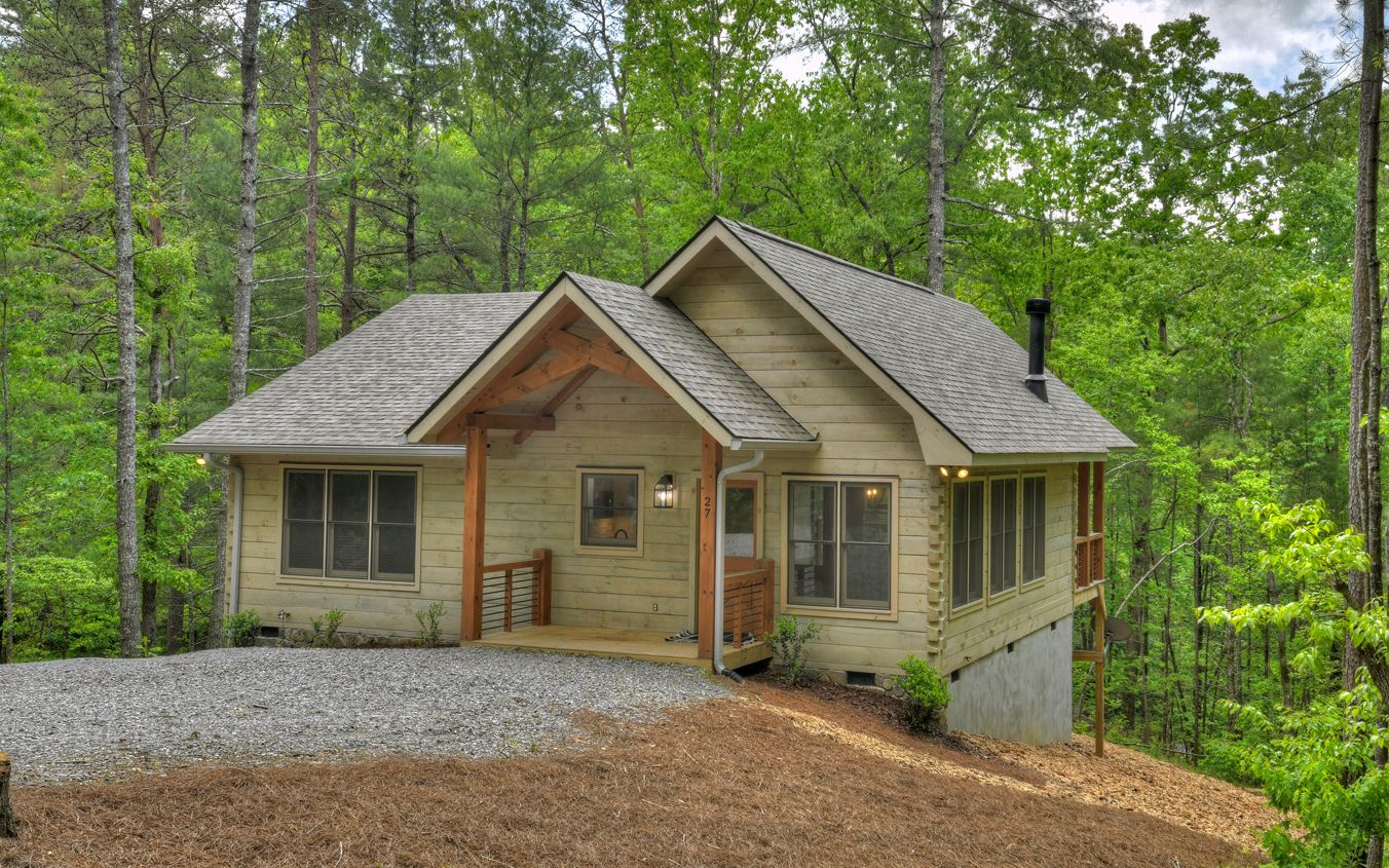 Situated on 2.57 acres and minutes from Blue Ridge, Ellijay, Rich Mountain Wildlife Preserve, waterfalls, hiking, and biking with easy access.This like new, true log cabin with 2BR, 2BH would make a great get-away, full time living, or rental. In the kitchen you will find custom cabinets, upgraded granite, tile backsplash, an island for extra work space, stainless appliances, and enough space for a large dining table! The living area boasts custom timber trusses and a stone and shiplap fireplace. You'll enjoy the extra windows for natural light with blinds for privacy when needed. Laundry, with like new washer and dryer, is centrally located to the sizable bedrooms. Primary bathroom has a large tile shower and both baths have upgraded granite. The finishes on this home really set it apart from the typical cabin. You have to see it in person to truly appreciate the inviting feel it offers.
