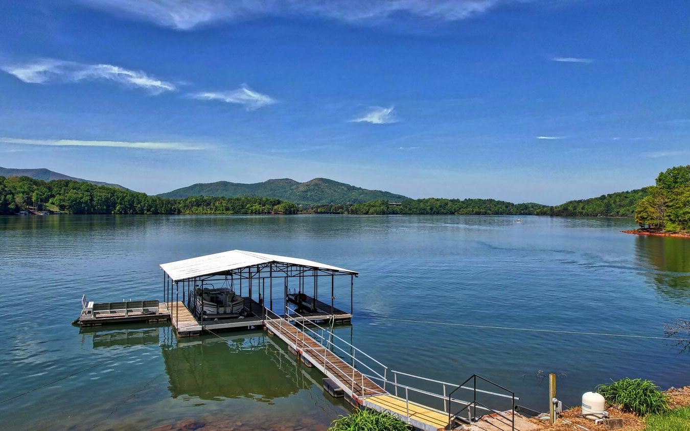 With over a football field of shoreline and boasting massive mountain and water views, this is one of the best deep-water properties to be found on Lake Chatuge! This wonderful, custom-built home is perfectly situated at the point of the peninsula and is on a gorgeous estate-sized, private 1.5-acre lot, with a wide open, gentle, grassy walk to the dock. Great outdoor space exists on both levels, and includes a lovely screened-in porch, Trex decking, hot tub, fire-pit, and lakeside picnic area, ripe for enjoying the peaking fall colors. The inside space oozes natural sunlight and is highlighted by a beautifully vaulted tongue & groove ceiling, hardwood floors, white kitchen cabinets and stainless appliances. Equipped with fiber optic internet, coax cable, phone, CAT-5 and ethernet in every room one can work from home seamlessly. This oasis offers the quintessential mountain/lake lifestyle! Once you arrive, you may never leave!